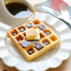 waffles on a white plate with syrup and ice cubes next to a cup of coffee