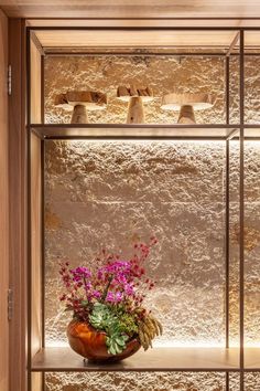 a vase filled with purple flowers sitting on top of a shelf next to a wall