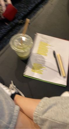 a person sitting at a table with a notebook and pen in front of them on the floor