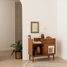 a small wooden cabinet sitting on top of a hard wood floor next to a white wall