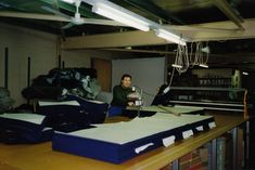 a woman sitting at a table with stacks of papers on top of it in an office