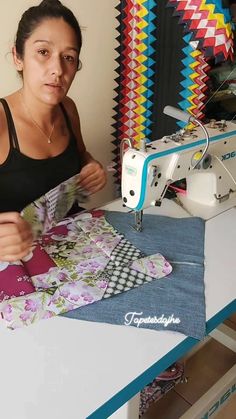 a woman sitting at a table with a sewing machine in front of her and some fabrics on the table