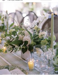 the table is set with candles, flowers and glass vases for centerpieces