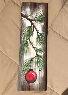 a piece of wood that has been painted with acrylic paint on it and is holding a red ornament