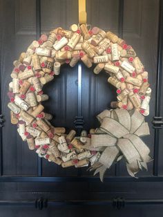 a wreath made out of wine corks is hanging on the front door with a bow