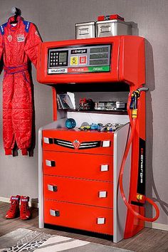 a room with a red car themed dresser and an orange racing suit hanging on the wall