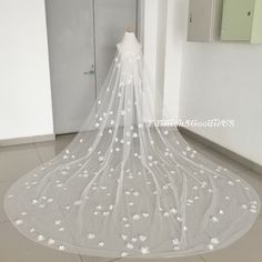 a wedding veil with white flowers on the bottom is hanging in front of a door