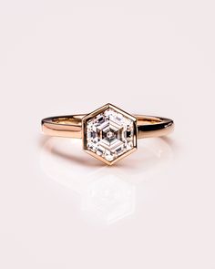 an engagement ring with a hexagonal cut diamond in the center on a white background