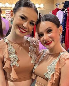 two young women standing next to each other in front of clothes on display at a store