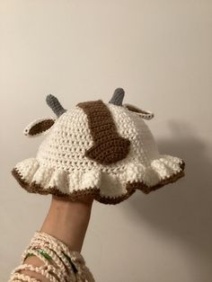 a hand holding a crocheted cow hat