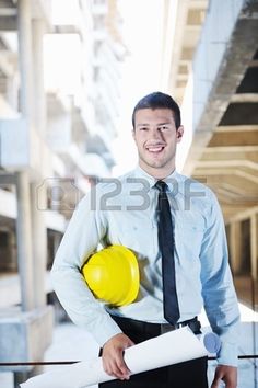 a man holding a yellow hard hat and blueprint while standing in an office building