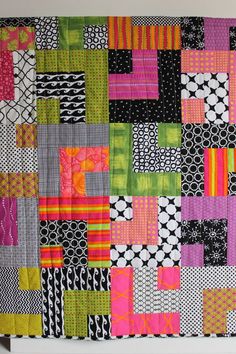 a colorful patchwork quilt hanging on the wall