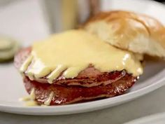 a close up of a sandwich on a plate with meat and cheese covered in sauce