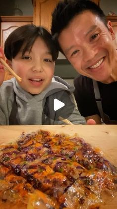 a man and child are posing for a photo with a pizza on the table in front of them