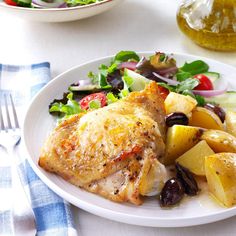 a white plate topped with chicken, potatoes and salad