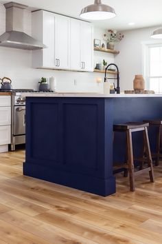 a kitchen with white cabinets and blue island