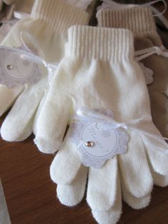 two white gloves sitting on top of a wooden table next to each other with tags