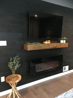 a living room with a fireplace and television mounted on the wall, surrounded by potted plants