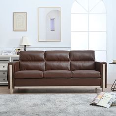 a brown leather couch sitting in a living room next to a white rug and table