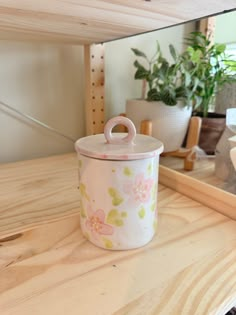 a pot sitting on top of a wooden counter next to a mirror and plant pots