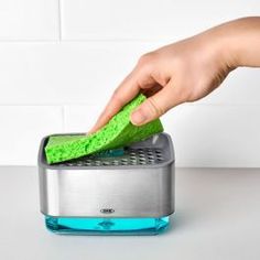 a person using a green sponge to clean a toaster