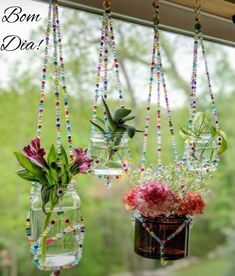 three vases filled with flowers hanging from a window sill next to each other