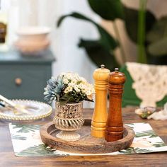 a wooden table topped with two salt and pepper shakers next to a potted plant