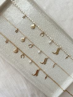 This multi charm necklace has a coastal cowgirl theme with dainty charms that spark joy whenever you wear it! Each necklace is made with non-tarnish, long lasting, and sensitive skin safe 14K Gold Filled and is sure to be a treasured keepsake for years to come! * Choose your 14K Gold Filled or Genuine Pearl chain style * Choose your length * All charms, chains and accents are made with 100% 14K Gold Filled hypoallergenic materials ✨ Create your own customized necklace here! https://shorturl.at/jvzY3 GET TO KNOW MAGBEE JEWELRY! ✨  🤍 All MagBee pieces are safe for sensitive skin and made with hypoallergenic Gold Filled or 925 Sterling Silver. 🤍 I only use real/natural gemstones and Pearls. 🤍 Most items are made to order just for you and have a 2-4 day processing time. 💌 All domestic orde Coastal Cowgirl Jewelry, Fresh Pearl Necklace, Cowboy Boot Necklace, Pearl Charm Necklace, Pretty Ear Piercings, Hawaii Trip, Cowgirl Jewelry, Coastal Cowgirl, Charm Necklaces