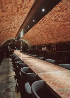 an empty wine cellar with rows of bottles on the wall and tables lined up against the wall