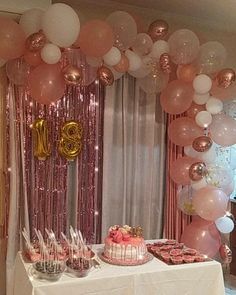 a table topped with lots of pink and white balloons next to a cake covered in confetti