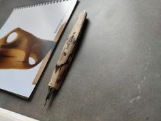 a pen sitting on top of a desk next to a spiral notebook with an image of a woman