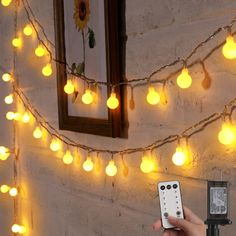 a person holding a remote control in front of a wall with lights and mirrors on it