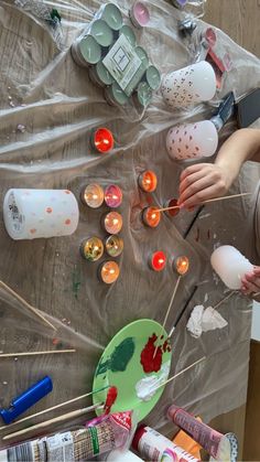 a table with candles, paint and other crafting supplies on it's surface