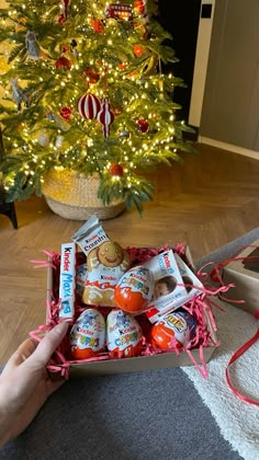 someone is holding an open box of eggs in front of a christmas tree with lights