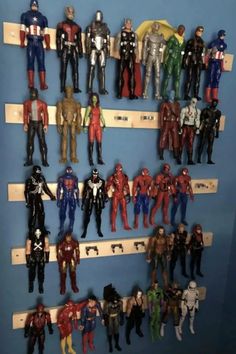 a bunch of action figures are lined up on the shelf in front of a blue wall