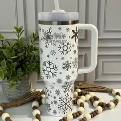 a white coffee cup sitting on top of a table next to a beaded necklace