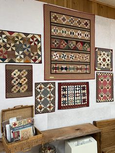 several quilts are hanging on the wall in a room with wooden furniture and baskets