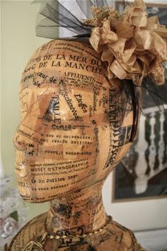 a wooden mannequin head with a flower on it's top and words all over the face