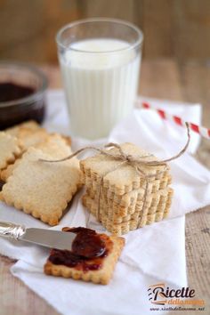 crackers and jam are sitting on a napkin next to a glass of milk