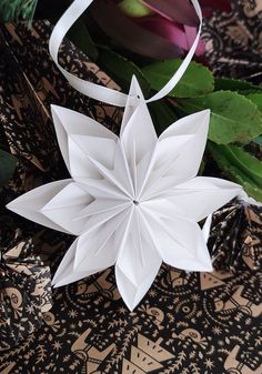 a white origami flower sitting on top of a table next to some flowers