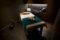 a treatment room with a bed and two vases on the table in front of it