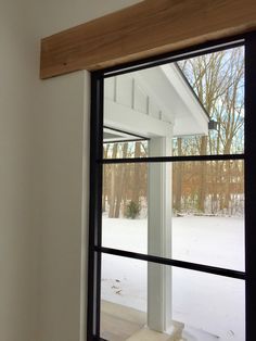 an open window in a white house with snow on the ground and trees behind it