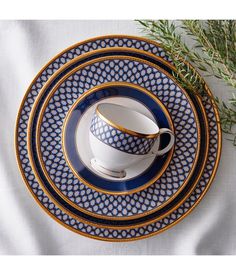 a blue and white plate with two cups on top of it, next to a sprig of rosemary