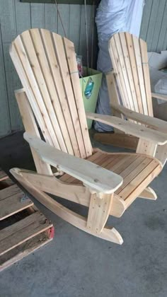 two wooden chairs sitting next to each other on top of a cement floor in front of a building