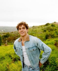 a young man standing in a field with his hands on his hips