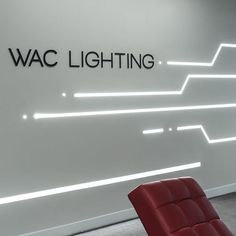 a red chair sitting in front of a white wall with the words wac lighting on it