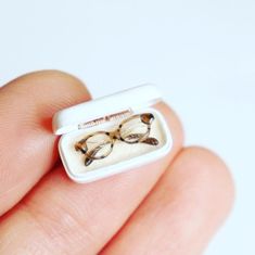 a miniature ring with glasses on it sitting in someone's hand and wearing them