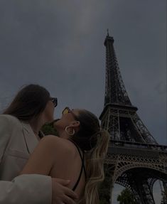 two people standing in front of the eiffel tower kissing each other with their eyes closed