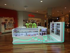 three women in green shirts standing behind a display case