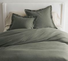 a bed with green sheets and pillows on it